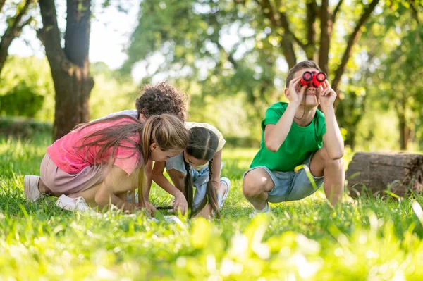 Niño con prismáticos y amigos cerca del mapa — Foto de Stock