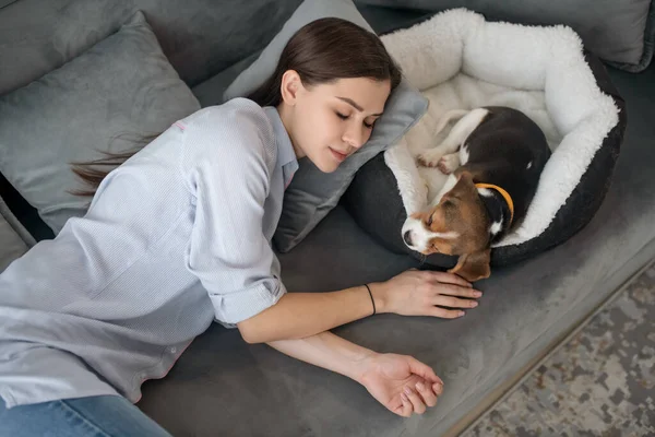 En ung kvinna som ligger bredvid sin valp och tar en tupplur — Stockfoto