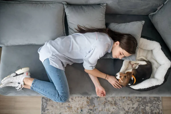 Een jonge vrouw ligt naast haar puppy en doet een dutje — Stockfoto