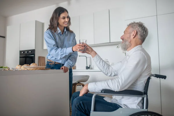 Joven mujer morena preparando el desayuno para su marido discapacitado — Foto de Stock