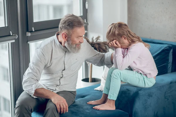 Чоловік розмовляє зі своєю засмученою маленькою донькою — стокове фото