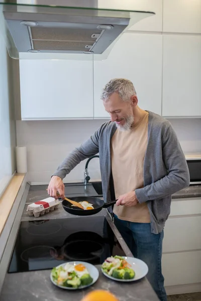 A mature beraded man cooking in the kicthen