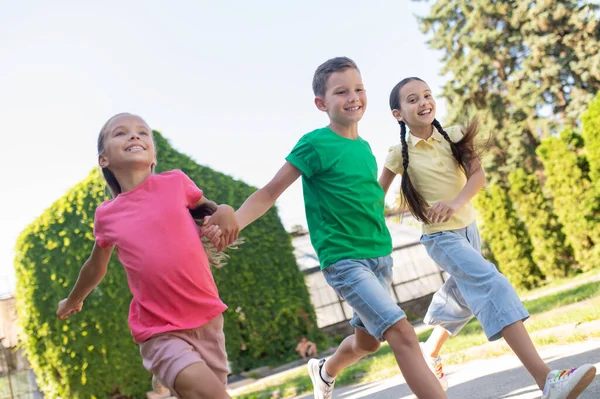 Мальчик и две девочки бегут в парке — стоковое фото