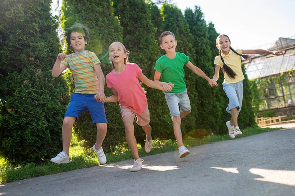 Niñas y niños saltando cogidos de la mano — Foto de Stock