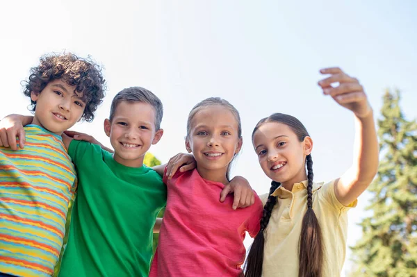 Abrazando sonrientes amigos en edad escolar al aire libre — Foto de Stock