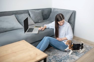 Evde çalışan bir kadın, yanında köpek yavrusu oynayan.