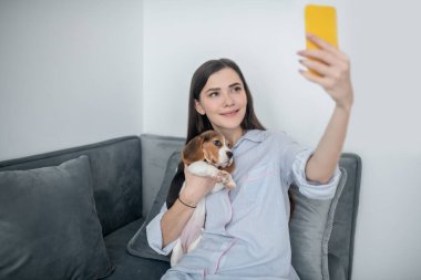 Şirin bir genç kadın köpeğiyle selfie çekiyor.