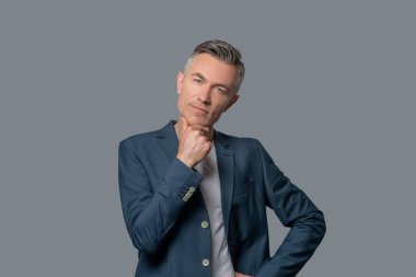 Düşünceli bir adam eliyle çenesine dokunuyor.