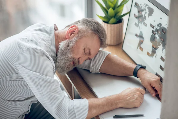 Mężczyzna śpiący w miejscu pracy czuje się zmęczony. — Zdjęcie stockowe