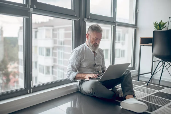 Muž sedící na podlaze a pracující na laptopu — Stock fotografie