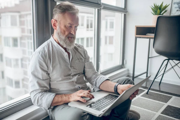 Ein Mann sitzt auf dem Boden und arbeitet an einem Laptop — Stockfoto