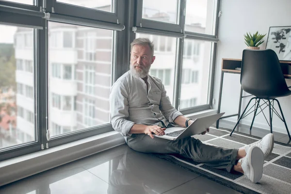 Muž s laptopem sedícím na podlaze a pracujícím na laptopu — Stock fotografie