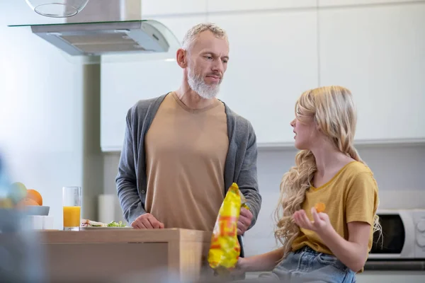 Блондинка сидить на кухні і розмовляє зі своїм батьком — стокове фото