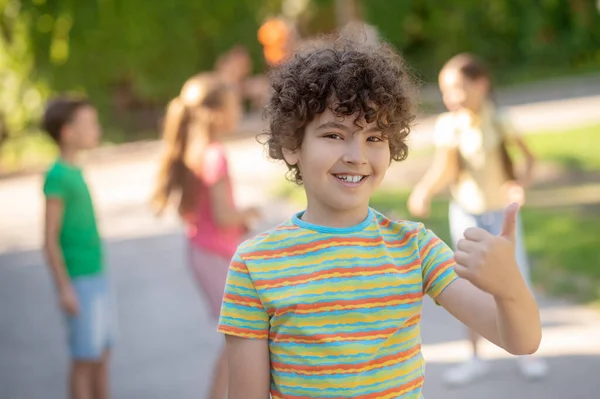 Vreugdevolle jongen toont ok gebaar in het park — Stockfoto