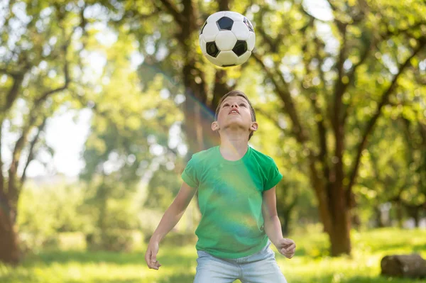 Rapaz atento a olhar para a bola de futebol no ar — Fotografia de Stock