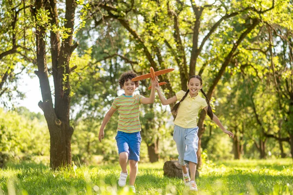 Garçon et fille courir avec jouet avion — Photo