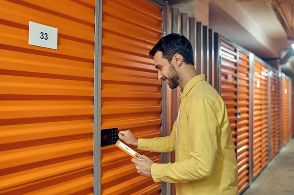 Hombre con la tableta cerca de combinación de cerradura de la puerta del garaje — Foto de Stock