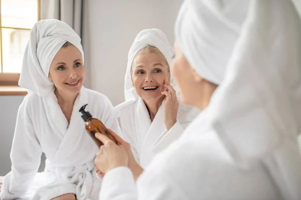Trzy kobiety badające skład produktu kosmetycznego — Zdjęcie stockowe
