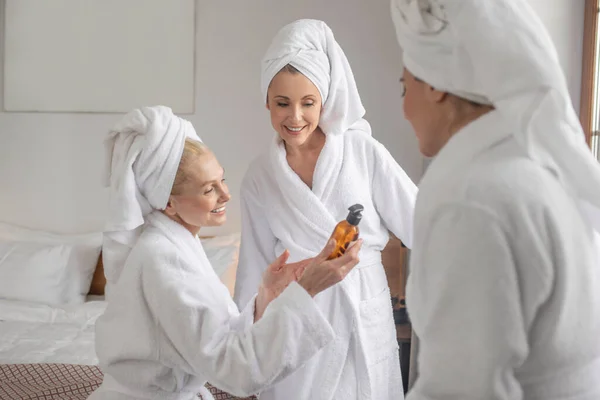 Mujeres en albornoces discutiendo nuevo producto cosmético — Foto de Stock