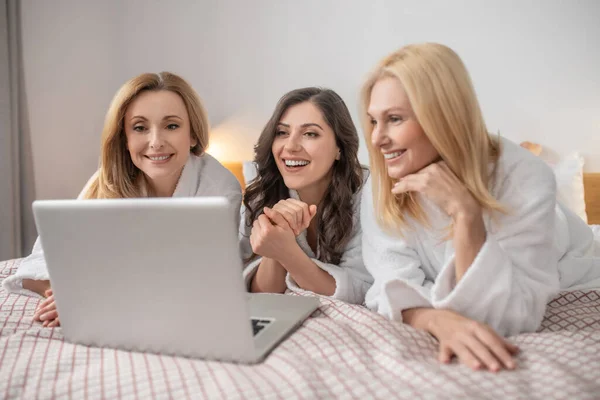 Ženy středního věku leží a dívají se na laptop — Stock fotografie
