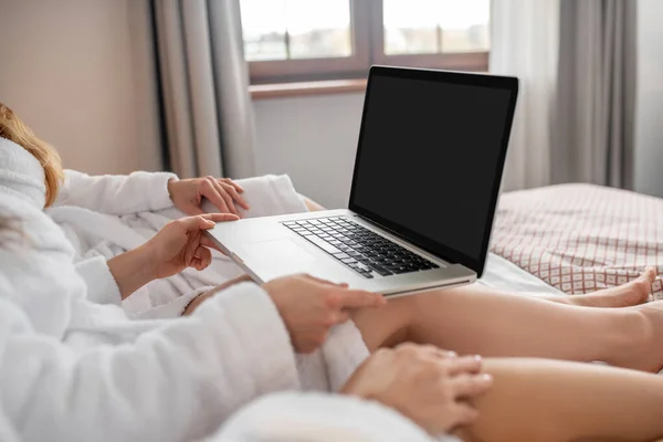 Γυναικεία χέρια κρατώντας ανοιχτό φορητό υπολογιστή στο κρεβάτι — Φωτογραφία Αρχείου