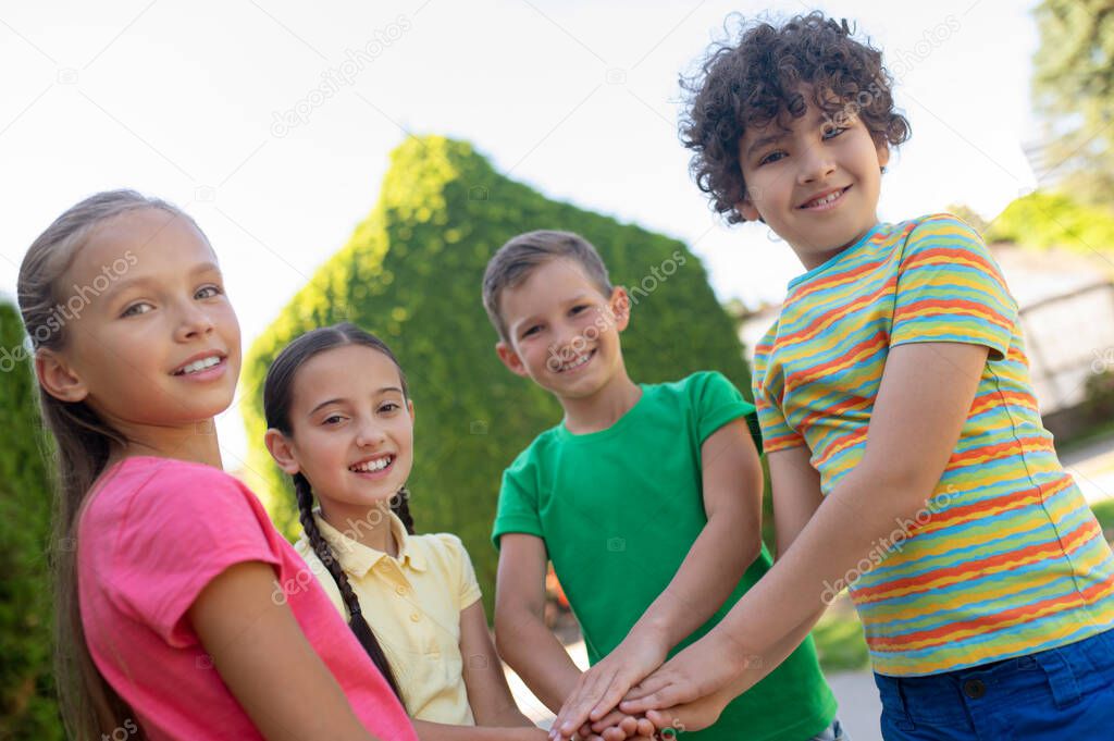 Happy children holding hands as sign of strong friendship