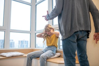 Gri saçlı bir adam ergen kızıyla zor bir konuşma yapıyor.