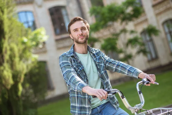 Une photo d'un jeune homme en chemise à plaid sur un vélo — Photo