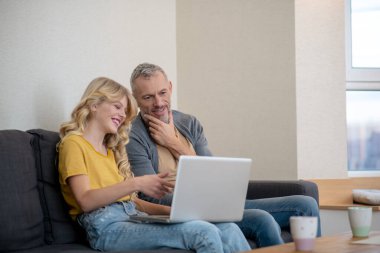 Baba ve kızı dizüstü bilgisayardan bir şey izliyor.