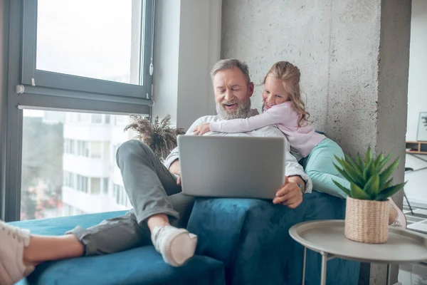 Ein Mann arbeitet, während seine kleine Tochter neben ihm sitzt — Stockfoto