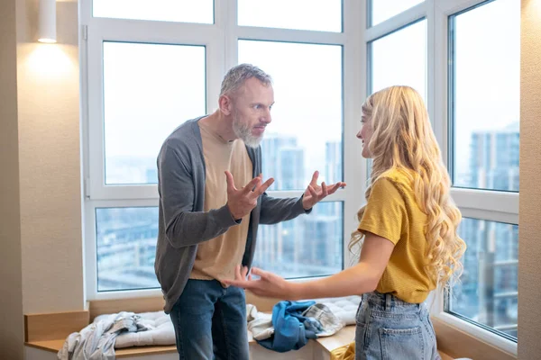 En blondine pige føler sig ked af det, mens hun har et skænderi med sin far - Stock-foto