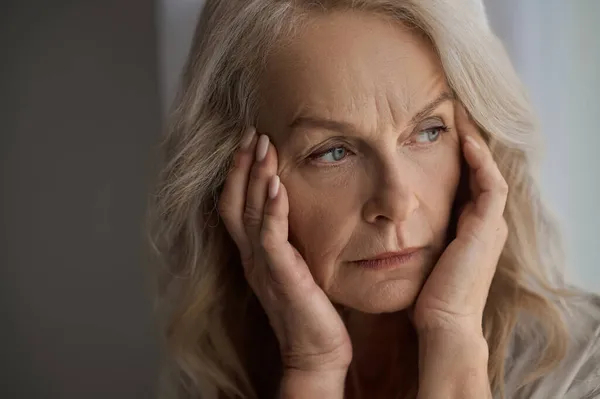 Droevige volwassen vrouw die last heeft van hoofdpijn — Stockfoto