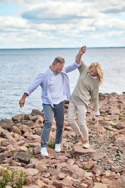 Wanita bahagia dan pria berjalan di sepanjang tepi laut — Stok Foto