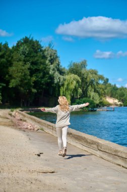 Denize yakın bir yerde kamera önünde koşan bir kadın.