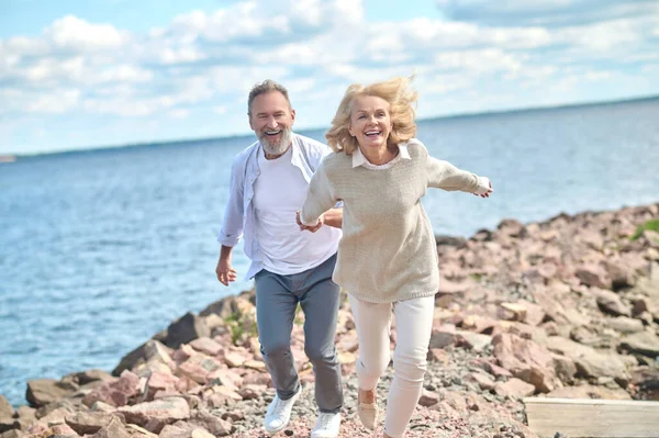 Захоплена жінка тримає руку чоловіка, що бігає на відкритому повітрі — стокове фото