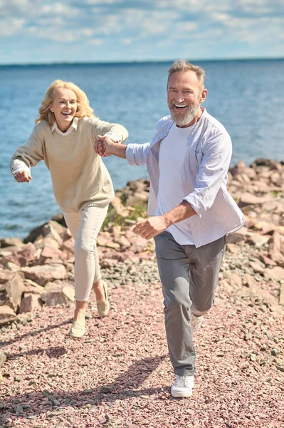 Сміється чоловік і жінка біжить біля води — стокове фото
