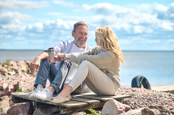 Спілкування чоловік і жінка сидять на землі біля моря — стокове фото