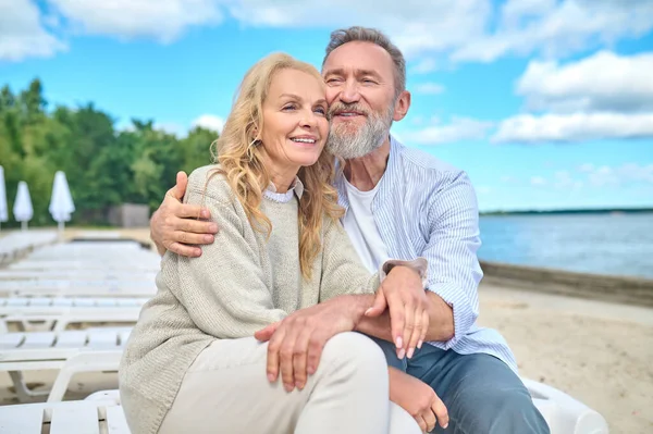 Hombre y mujer sonrientes sentados en la playa del mar — Foto de Stock