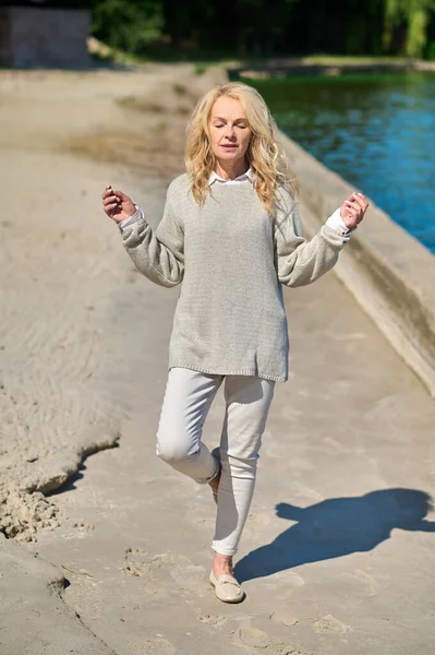 Vrouw met armen aan de zijkant opgeheven een been — Stockfoto