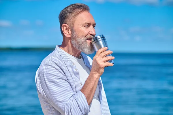 Man med dryck på bakgrunden av havet — Stockfoto