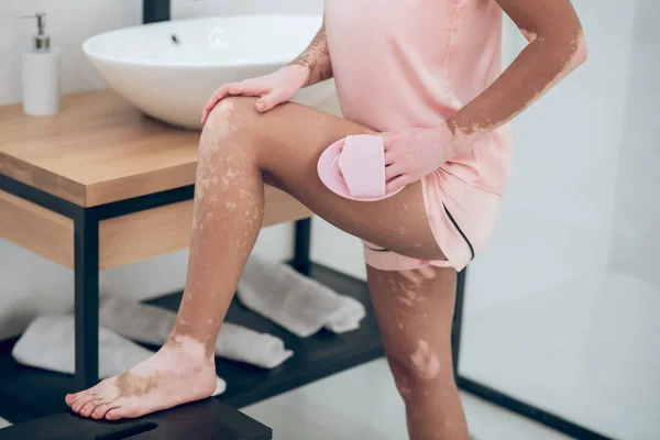 Een vrouw in roze lingerie masseren haar dijen — Stockfoto