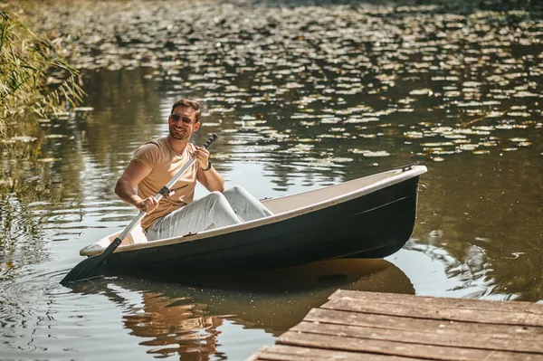 Smiling man with paddle in boat