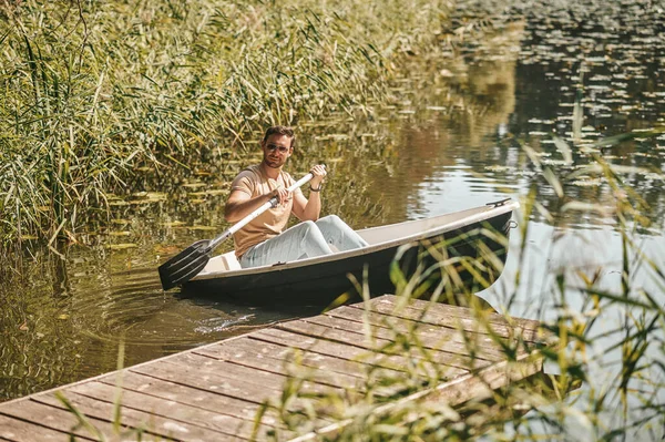 Homem com um remo no barco na água — Fotografia de Stock