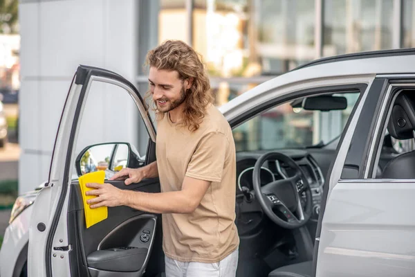 Neşeli genç adam arabanın kapısını temizliyor.