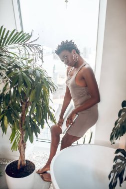 Dar bej elbiseli, koyu tenli, çekici bir kadın.