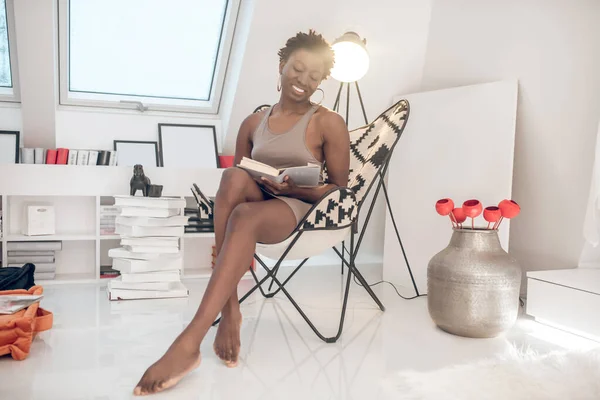 Une femme à la peau foncée avec un livre dans les mains assis — Photo