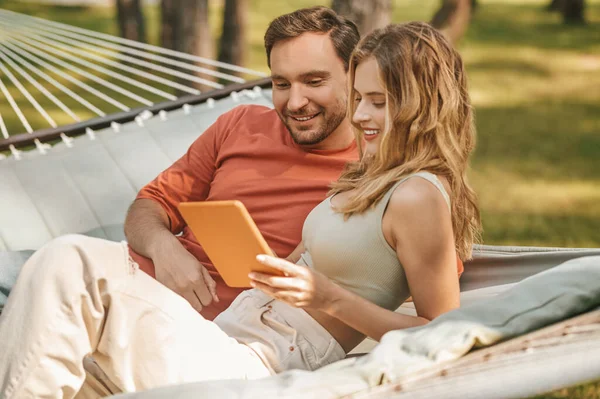 Feliz hombre y mujer buscando interesado en la tableta —  Fotos de Stock