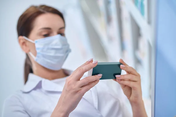 Mujer con máscara protectora mirando un paquete de medicamentos — Foto de Stock