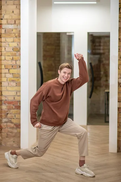 Nuori mies näyttää onnelliselta ja nauttinut toimistossa käytävällä — kuvapankkivalokuva