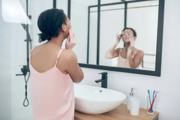 Una mujer en lencería rosa en un baño mientras hace procedimientos de belleza — Foto de Stock